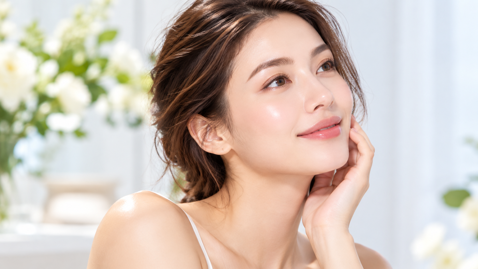 Model touching her cheek and smiling to illustrate hydrated, glowing skin