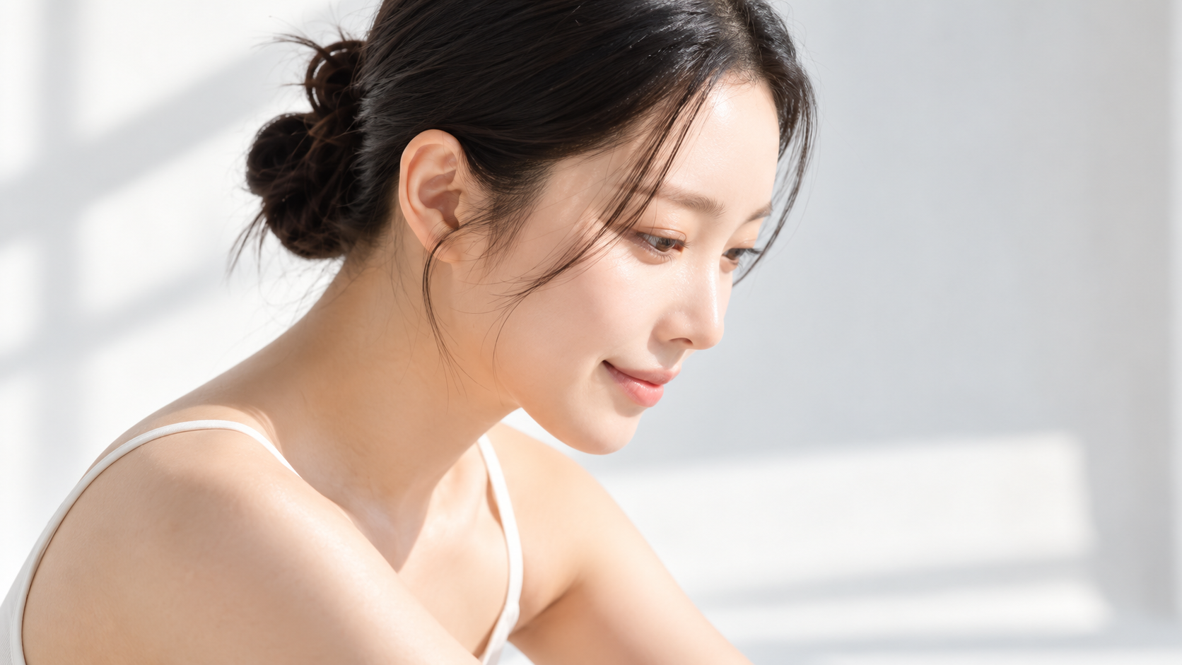 Model smiling softly in natural light to show clear, glowing skin
