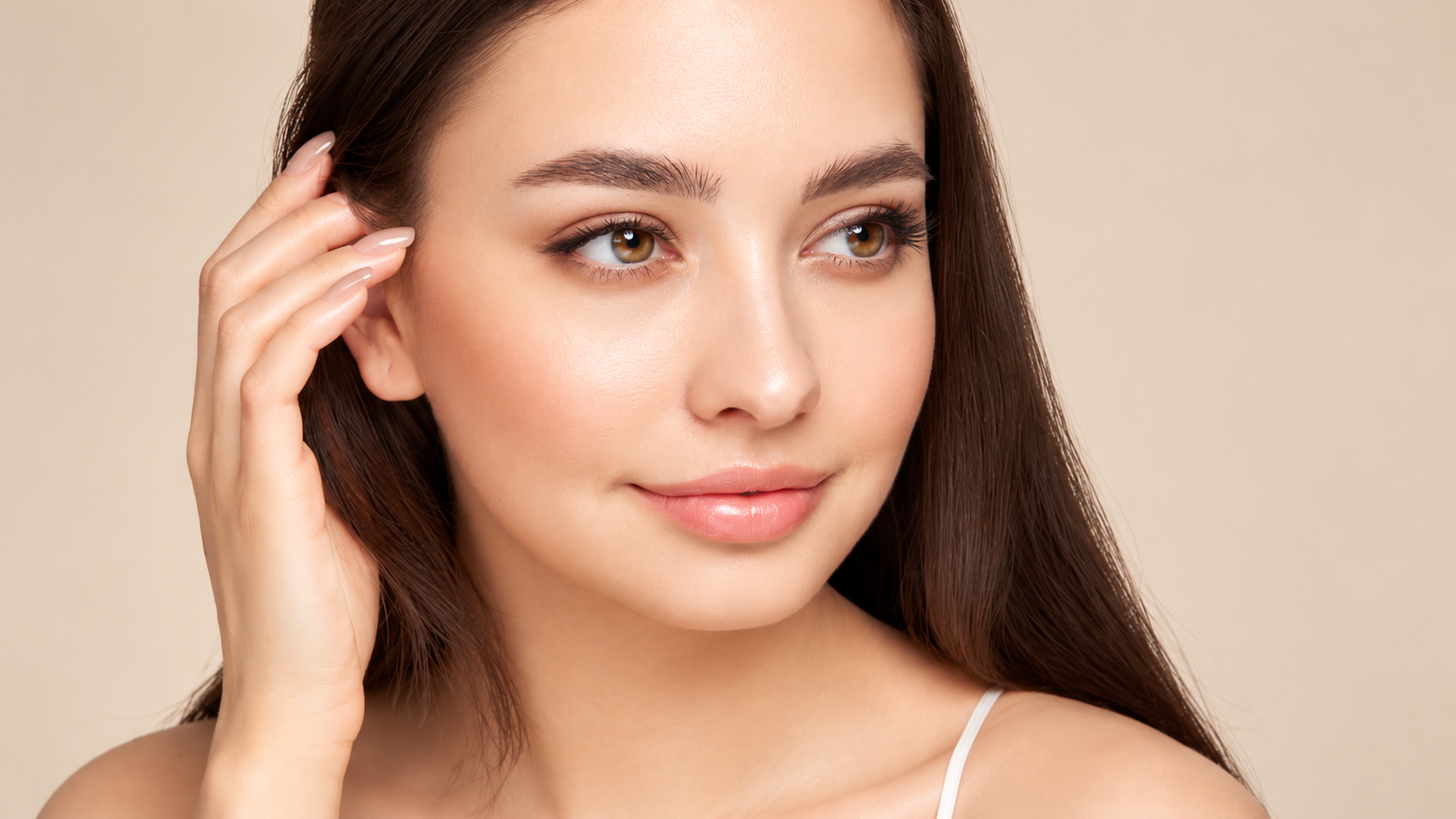 Model tucking her hair behind her ear to illustrate bright, smooth skin around the eyes