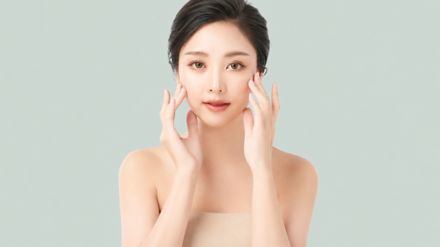 Model touching her cheeks with both hands to illustrate firm, even-toned skin