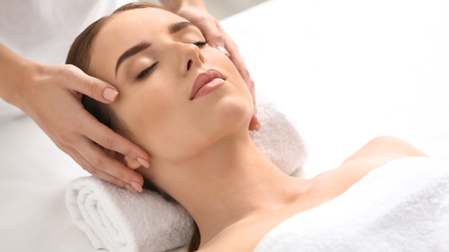 Practitioner gently massaging a patient's temples during a facial treatment