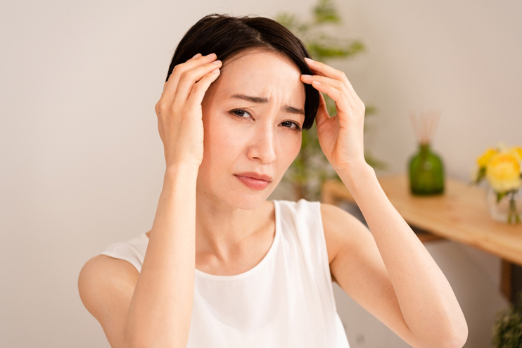 Woman touching her forehead with both hands.