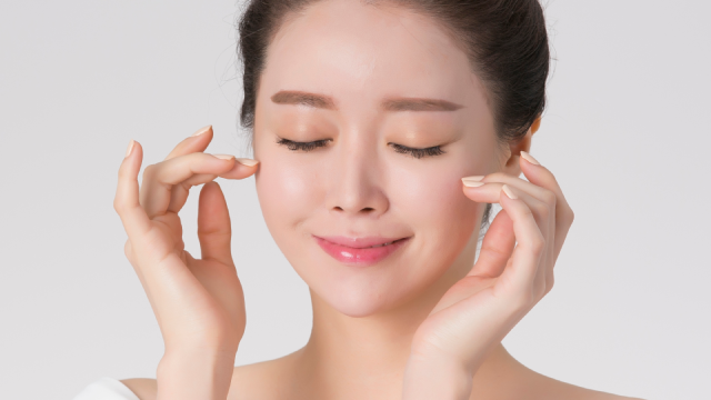 Model with closed eyes touching her temples to illustrate smooth skin around the eyes