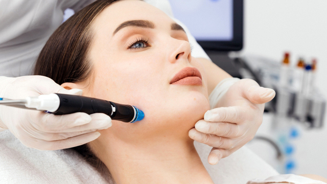 Practitioner performing a facial treatment on a woman.
