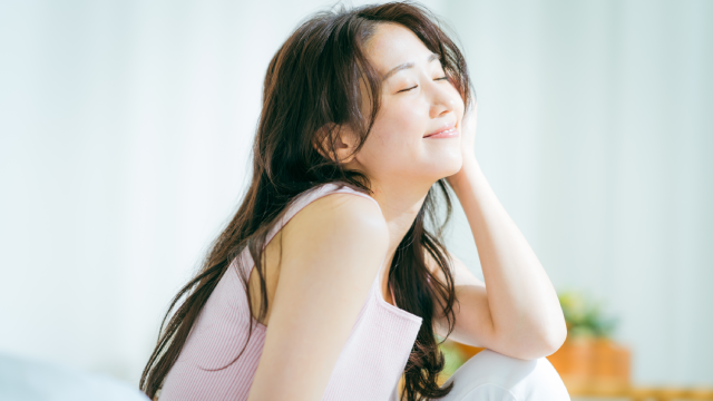 Smiling model resting her cheek on her hand to illustrate relaxed, refreshed skin