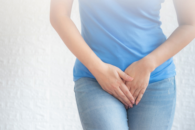 A woman standing with her hands gently placed over her lower abdomen and pelvic area, representing women’s intimate health concerns, pelvic discomfort, or gynecological care.