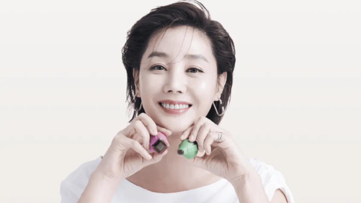 Smiling woman holding Thermage FLX treatment tips near her jawline, representing non-surgical skin lifting and anti-aging dermatology care