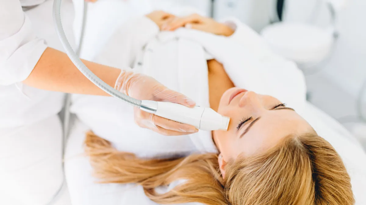 Woman receiving IPL laser treatment on her cheek with a handheld device