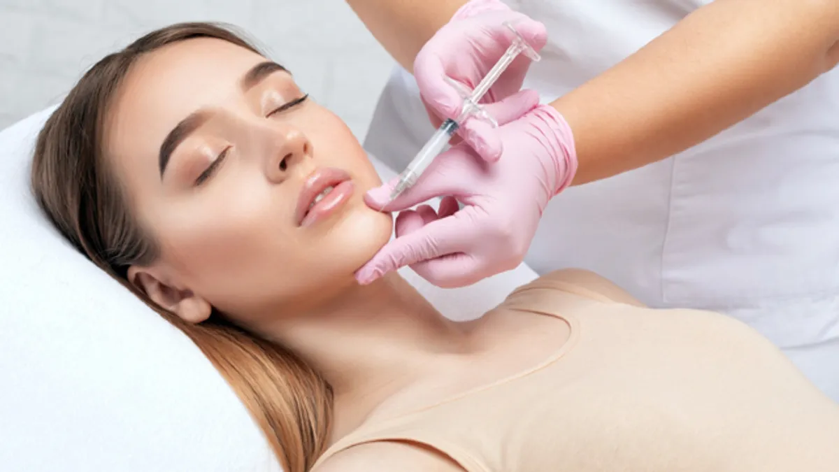 Woman receiving a skin booster injection along the jawline from a dermatology specialist for improved skin hydration and texture