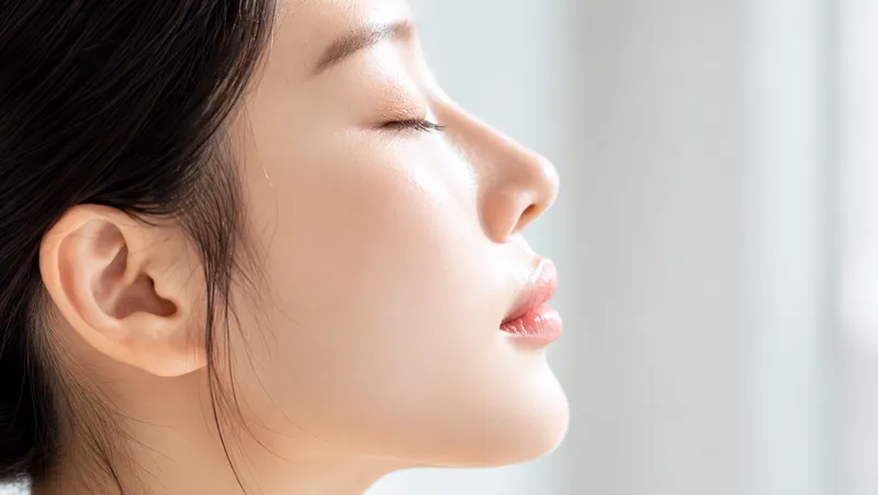 Close-up side profile of a woman with eyes closed in soft natural light.