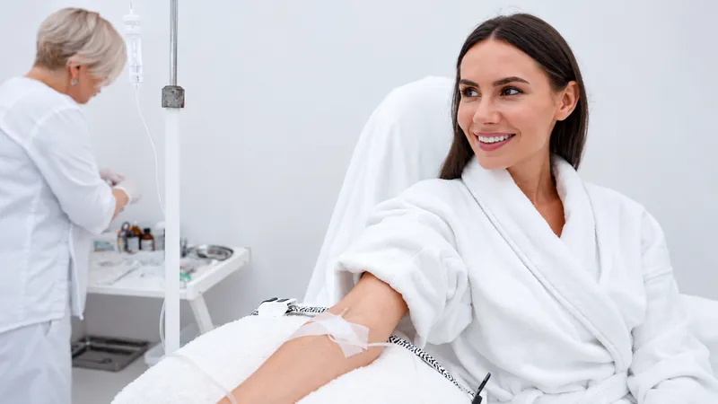 Woman receiving an IV infusion while seated in a treatment room.