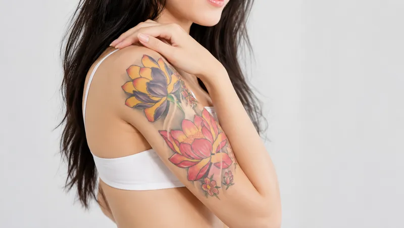 Woman showing a colorful floral tattoo on her upper arm.