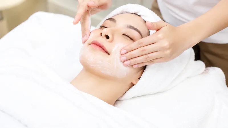 Practitioner applying cream to a woman’s face during treatment.