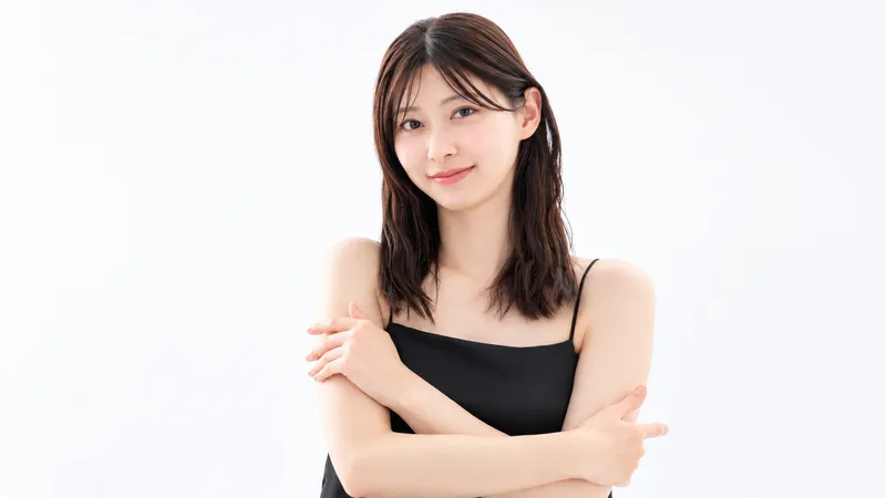 Woman in a black sleeveless top facing the camera with arms crossed.