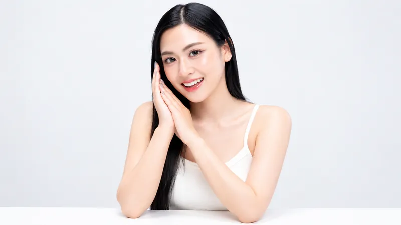 Woman smiling with her hands together beside her face.