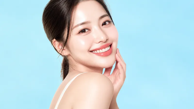 Smiling woman touching her cheek against a blue background.