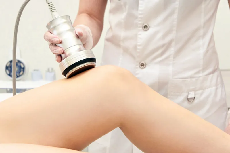 Practitioner applying a handheld device to a woman’s thigh.