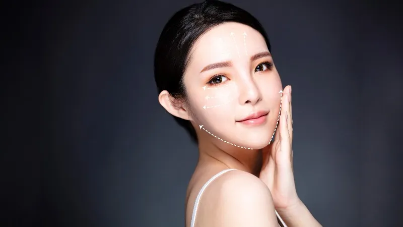 Woman touching her cheek with facial contour arrows shown.