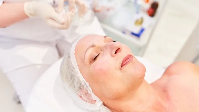 Gloved practitioner attending to a woman lying on an examination bed.
