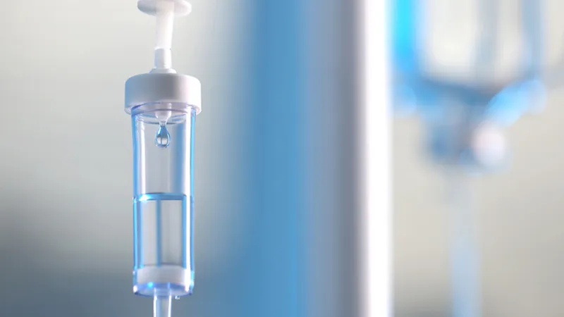 Close-up of an IV drip chamber with clear fluid.