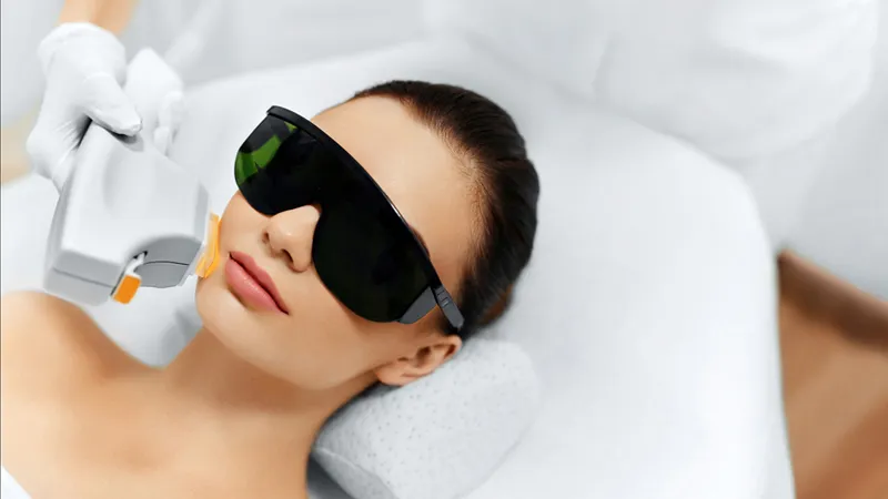 Practitioner applying a light-based device to a woman’s cheek.