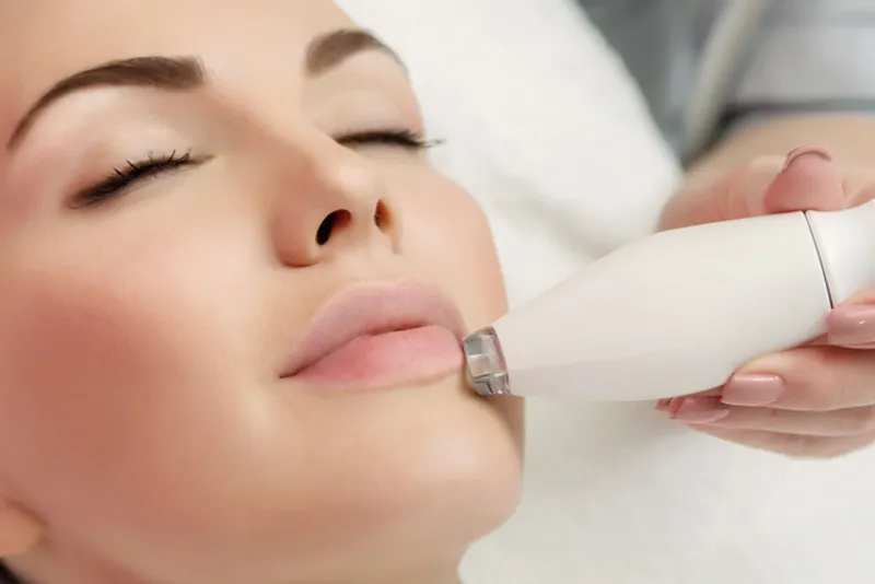 Practitioner applying a handheld device to a woman’s chin.