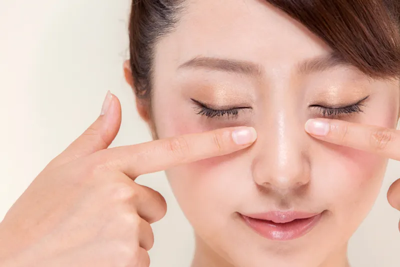 Woman gently touching both under-eye areas to illustrate dark circle and under-eye concerns.
