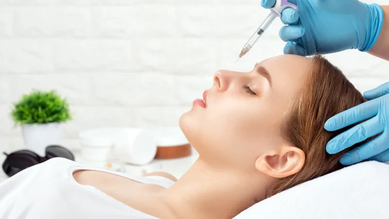 Patient receiving a nose filler injection from a doctor during a cosmetic consultation.