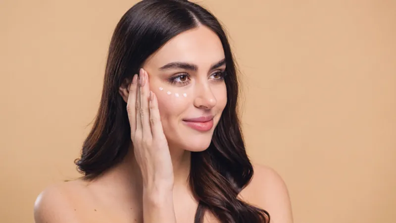 Woman gently applying cream under her eyes.