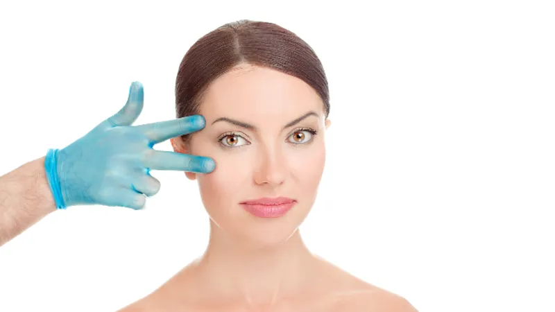 Patient showing facial recovery after brow lift surgery, with a gloved hand indicating the eye and brow area.