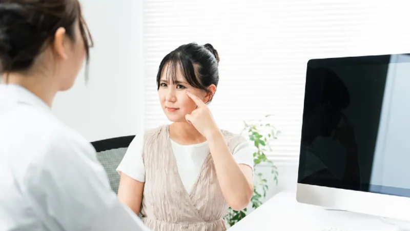 Double eyelid surgery consultation: a woman points to her upper eyelid to show the doctor the crease she wants