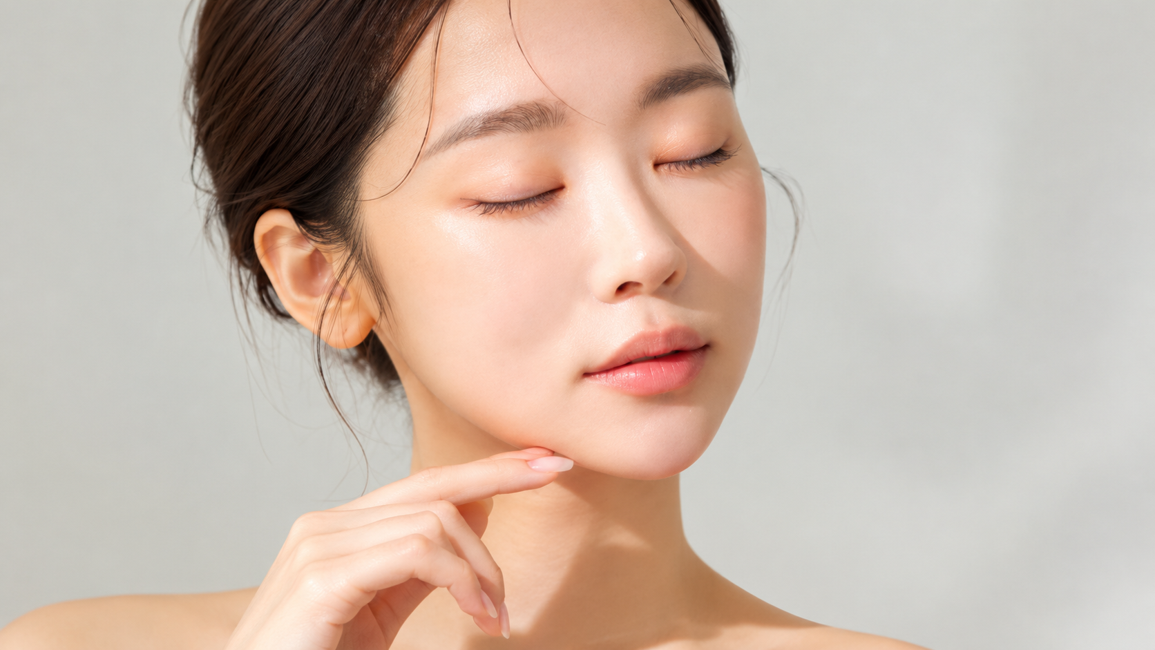 Woman with closed eyes gently touching her chin, highlighting her facial contours.
