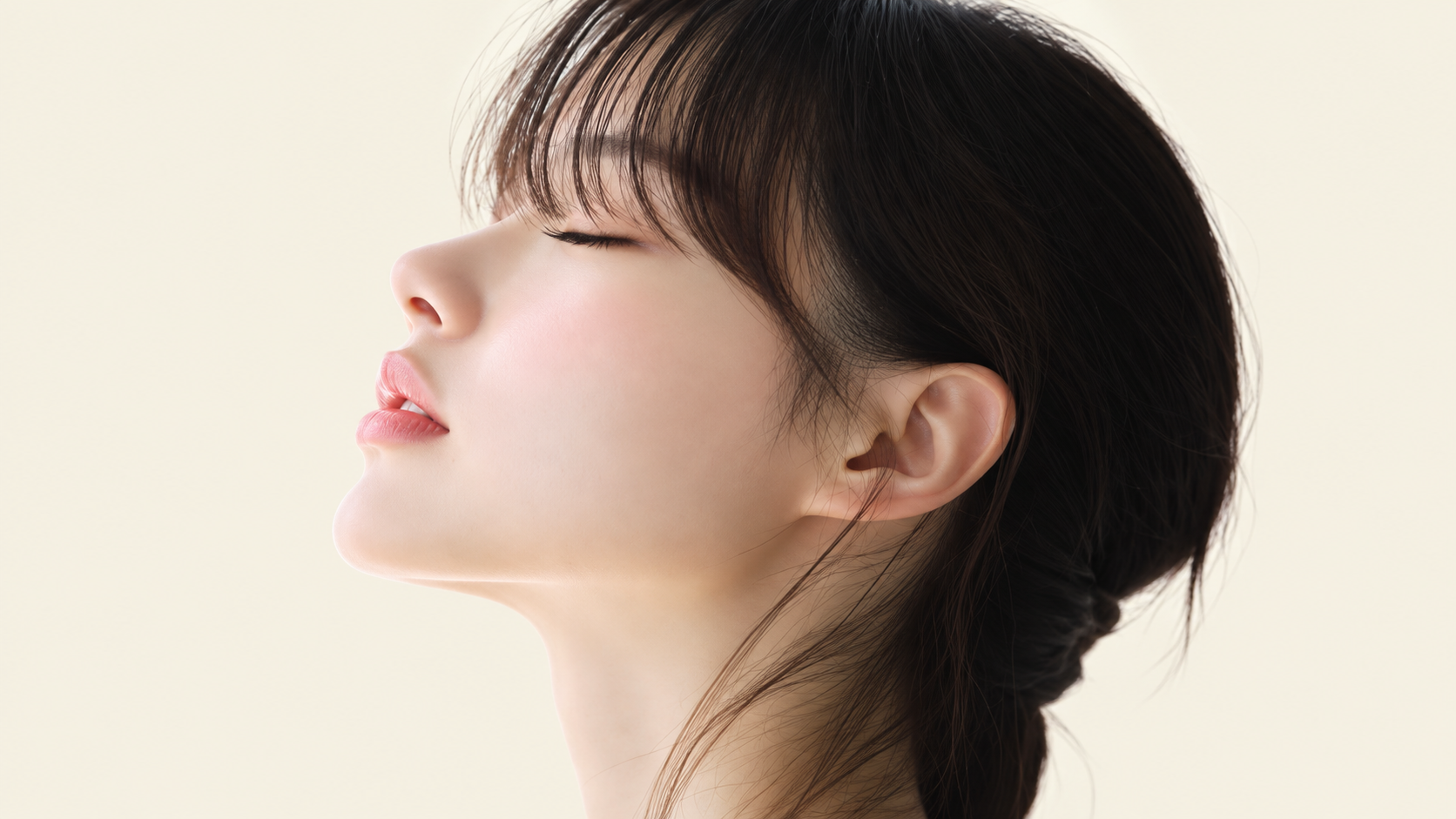 Woman in side profile with dark hair against a light background.