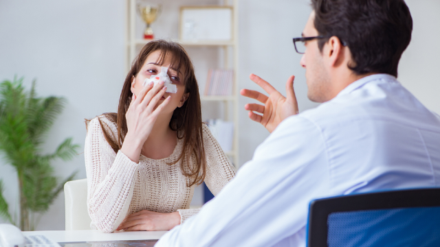 Post-rhinoplasty patient with nasal bandage at a second week surgical follow-up consultation