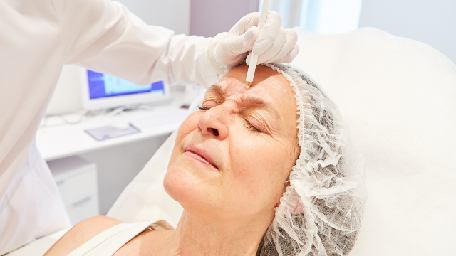 Doctor marking a patient’s forehead before forehead lift surgery.