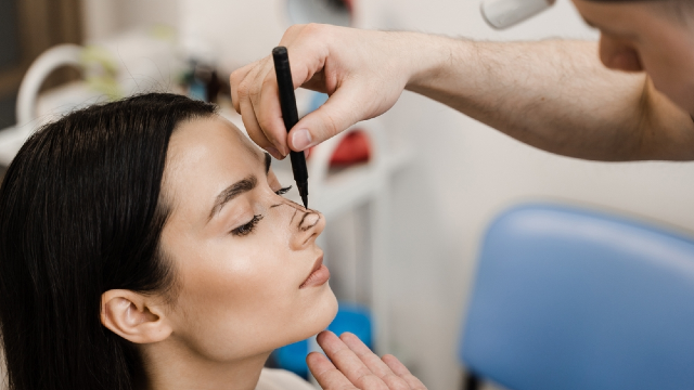 Plastic surgeon drawing preoperative markings on a patient's nose for revision rhinoplasty