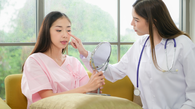 Doctor reviewing rhinoplasty results with a patient using a mirror during recovery