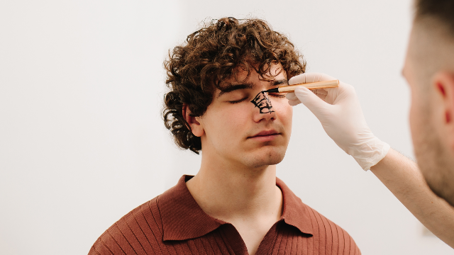 Doctor marking a male patient’s nose during a rhinoplasty assessment.