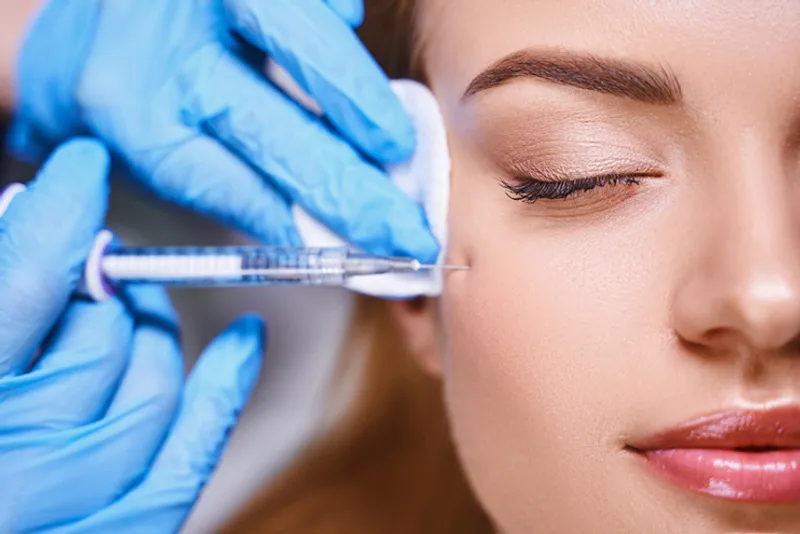 Practitioner injecting the outer eye area with a syringe.