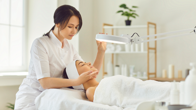 Practitioner examining a woman’s face during a skincare treatment.