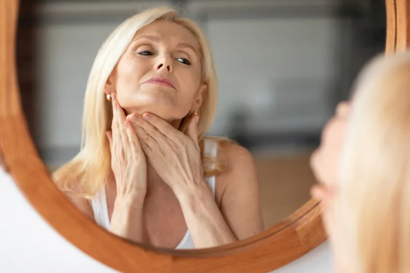 Woman examining her neck in a mirror.
