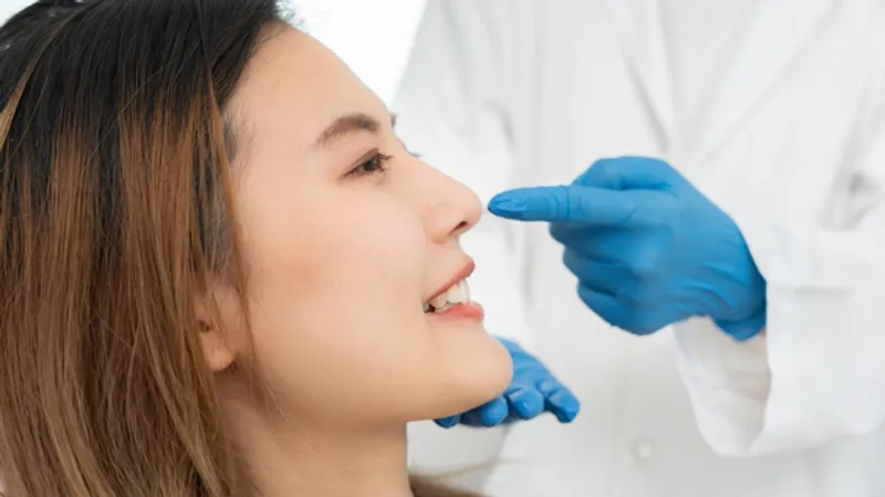 Practitioner examining a woman’s nose while wearing medical gloves.