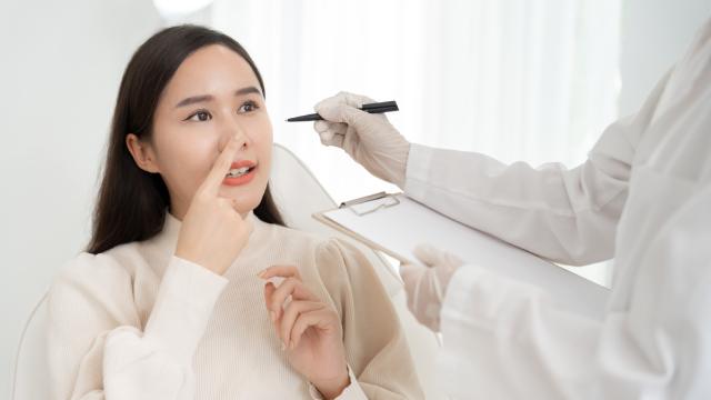 Doctor discussing a nose consultation with a woman pointing to her nose.