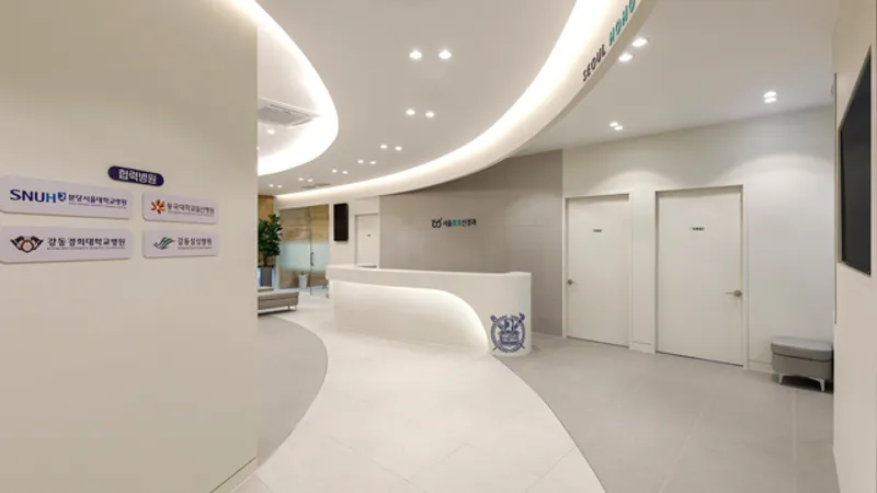 Reception area at Seoulhoho Hospital with a curved white desk, seating, and consultation room doors.