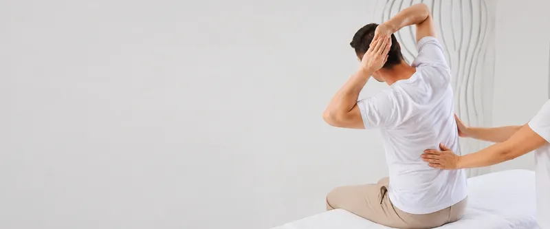 Woman in workout clothing holding her lower back with both hands.